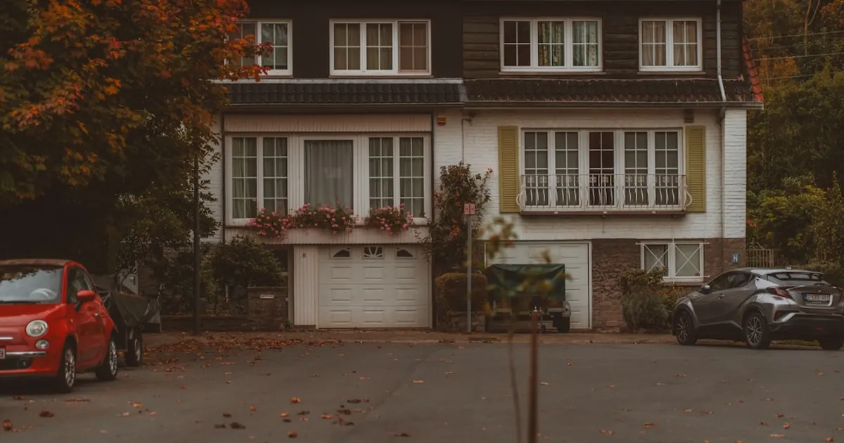 Two cars parked outside a suburban house in autumn.