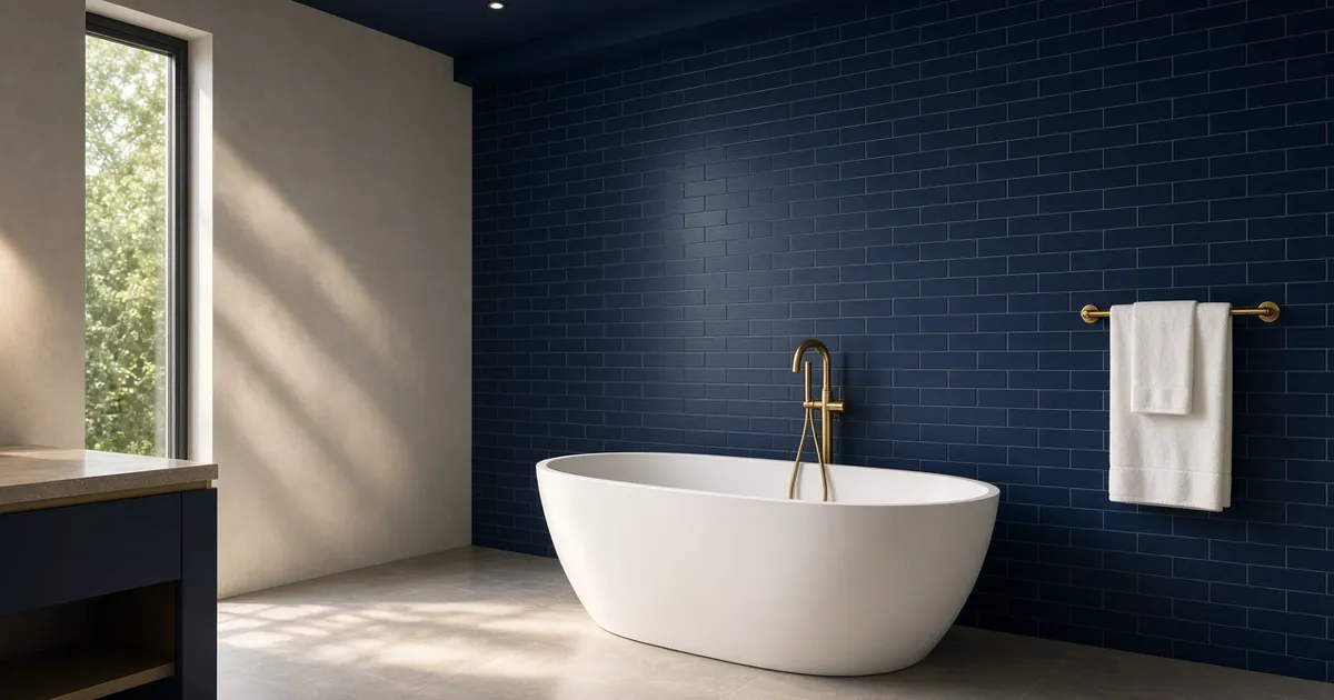 A freshly renovated bathroom with navy tile, a freestanding white tub, and brass fixtures